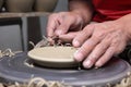 Potter's hands finishing clay plate