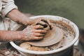 The potter's hands formed clay pot on a potter's wheel. The master potter works in a workshop