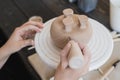 The potter`s woman hands are shaping a cup from a clay. The process of creating pottery. The master ceramist works in Royalty Free Stock Photo