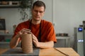 Potter sculpts a patterned cylinder from clay.