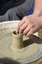 Potter at small wheel with pot