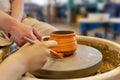 The Potter with student coloring a pot on a Potter& x27;s wheel