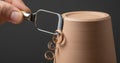 Potter trimming unfired clay pot with a loop tool, creating delicate clay curls against a dark background. Royalty Free Stock Photo