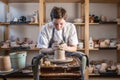 Potter working on a Potter`s wheel making a vase. Young woman forming the clay with hands creating jug in a workshop Royalty Free Stock Photo