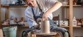 Potter working on a Potter`s wheel making a vase. Young woman forming the clay with hands creating jug in a workshop Royalty Free Stock Photo