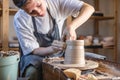 Potter working on a Potter`s wheel making a vase. Young woman forming the clay with hands creating jug in a workshop Royalty Free Stock Photo