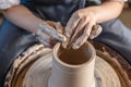 Potter working on a Potter`s wheel making a vase. Woman forming the clay with hands creating jug in a workshop. Close up