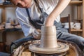 Potter working on a Potter`s wheel making a vase. Young woman forming the clay with hands creating jug in a workshop Royalty Free Stock Photo