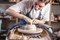 Potter working on a Potter`s wheel making a vase. Young woman forming the clay with hands creating jug in a workshop Royalty Free Stock Photo