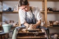 Potter working on a Potter`s wheel making a vase. Young woman forming the clay with hands creating jug in a workshop Royalty Free Stock Photo