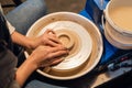 on a potter& x27;s wheel, a young potter makes a preparation for a pot out of clay.