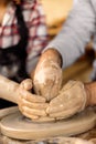 Potters hands guiding a woman hands to help her to work with the ceramic wheel Royalty Free Stock Photo