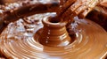 A potters wheel spins as skilled hands work to shape a lump of clay into a tall vase.