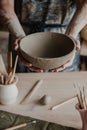 Pottery, clay, ceramics art concept - closeup on hands of young master with the large plate from fireclay Royalty Free Stock Photo