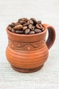 Pottery espresso cup full of coffee beans on the cloth. Royalty Free Stock Photo