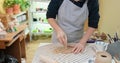 Pottery female ceramist master in apron standing at work table in studio working cutting and trimming clay with fettling