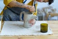 Pottery hobby or ceramic manufacture small business: young artist molding jug of raw clay in studio Royalty Free Stock Photo