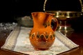 Pottery jug to serve wine or water on an embroidered table mat