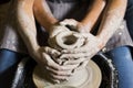 Pottery making. Smeared in clay hands of man and woman on potter`s wheel Royalty Free Stock Photo