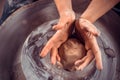 Potter master woman at his wheel creating a new masterpiece. National craft. Close-up.