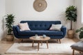 Pouf on blue carpet in bright living room interior with grey chair and settee against the wall with gallery