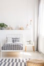 Pouf on patterned carpet near grey bed in white kid`s bedroom in Royalty Free Stock Photo