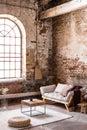 Pouf and table on rug in spacious loft interior with window. Real photo