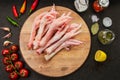Poultry meat. Turkey legs lie on a wooden board. Chicken legs with peppers and tomatoes on a black background Royalty Free Stock Photo