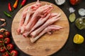 Poultry meat. Turkey legs lie on a wooden board. Chicken legs with peppers and tomatoes on a black background Royalty Free Stock Photo