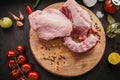 Poultry meat. Turkey neck lie on a wooden board. Chicken meat with peppers and tomatoes on a black background Royalty Free Stock Photo