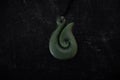 Pounamu fish hook necklace on dark background. Aotearoa, New Zealand, Maori. Royalty Free Stock Photo