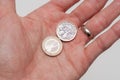 Pound coin and one Euro coin being held in a persons hand