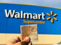 Pound currency note in hand in front of Walmart supermarket sign