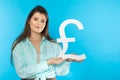 The girl holds a large pound symbol in her hands. Great Britain currency shape. Symbol of finance and cash flow in the Royalty Free Stock Photo