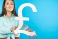 The girl holds a large pound symbol in her hands. Great Britain currency shape. Symbol of finance and cash flow in the Royalty Free Stock Photo