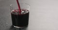 Pour berry juice in a thin wall glass on concrete countertop with copy space