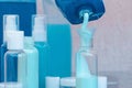 Pour blue shampoo in a small bottle of big. Travel set of jars. Bottle close-up. Royalty Free Stock Photo