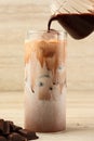 Pour Chocolate Thick Sauce to Tall Glass with Fresh Milk and Ice Royalty Free Stock Photo