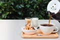 Pour coffee into cup on the table with cookie, milk and sugar at side. Royalty Free Stock Photo