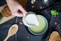 Pour cream into cream soup. Close-up. Milk jug with cream in female hands.