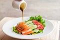 Pouring the dressing of Crab salad in white dish healthy food background