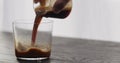 pour espresso in tumbler glass on black aok table