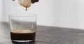 pour espresso in tumbler glass on black aok table