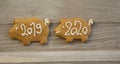 Pour feliciter 2020, gingerbread pig with year 2019 is followed by pig with 2020 sign, wooden background, Christmas stil life Royalty Free Stock Photo