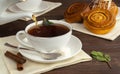 pour hot black tea into a white cup. aromatic tea with sugar and mint. delicious cinnamon rolls for breakfast. Royalty Free Stock Photo