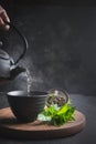 Pour hot tea with steam into cup on black table. Chinese tea Royalty Free Stock Photo