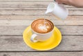 Pour milk to Coffee cup in wood background Royalty Free Stock Photo