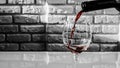 Pour red wine into a glass against a brick wall background Royalty Free Stock Photo