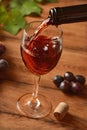 Pour red wine into the glass - wood background Royalty Free Stock Photo