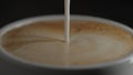 pour steamed milk into espresso in white cup closeup